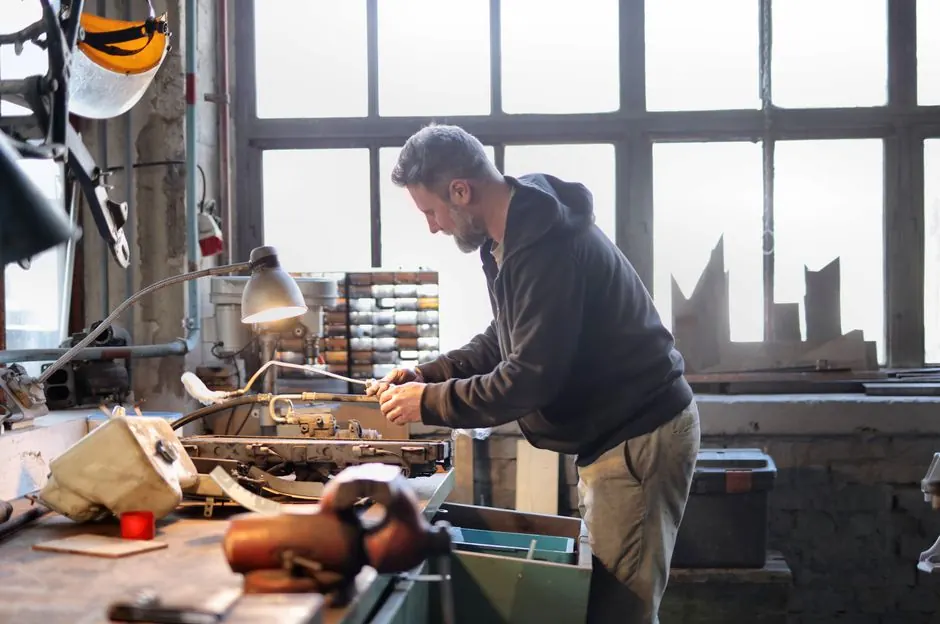 Experienced craftsman skillfully repairing equipment in a spacious and light-filled workshop.